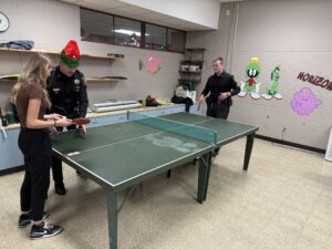 Student playing ping pong with security officers
