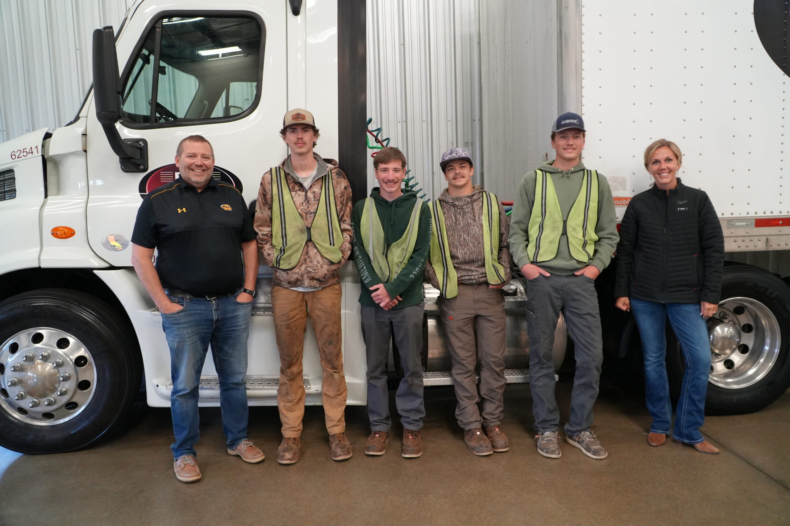 High school boys standing in front of semitruck for CDL program
