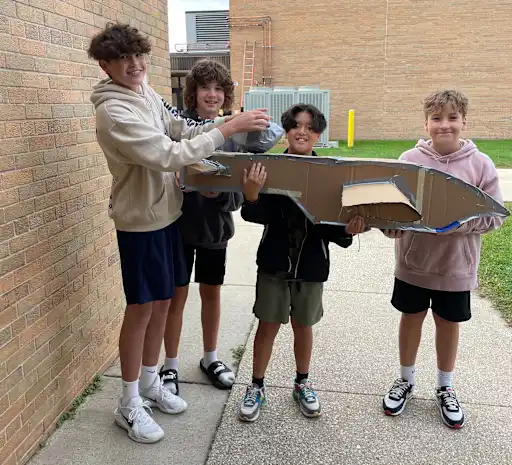 Boys holding cardboard airplane