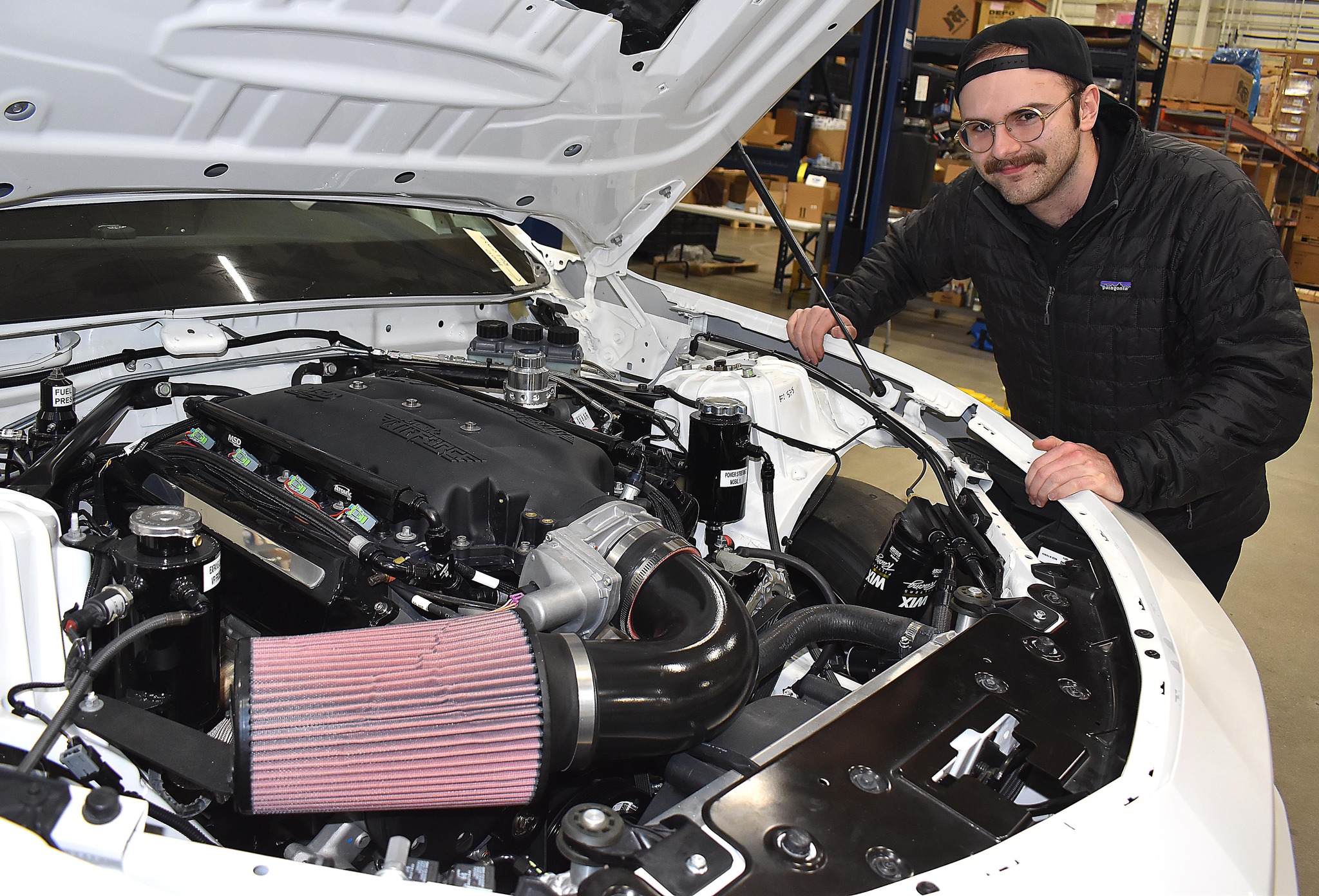 Student looking at engine of car
