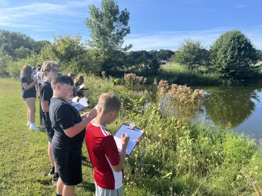 Kids by pond taking notes